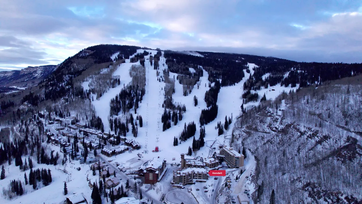 A vibrant exterior shot showcasing the snowy ski slopes right next to the resort buildings, surrounded by lush pine trees. Guests can be seen enjoying après-ski gatherings and relaxing in hot tubs, evoking a lively and adventurous family atmosphere.